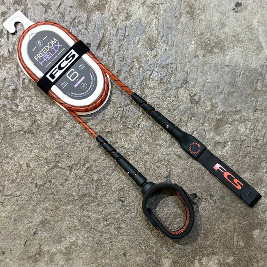 A FCS Freedom Helix Leash - All Round in red lying on a concrete floor