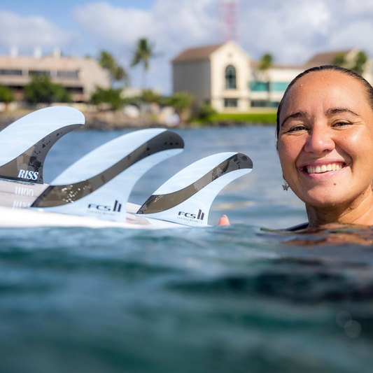 FCS II Carrisa Moore Signature Tri Fin Set - Blue and Black - Carrisa Moore in the water showing her fins in her board