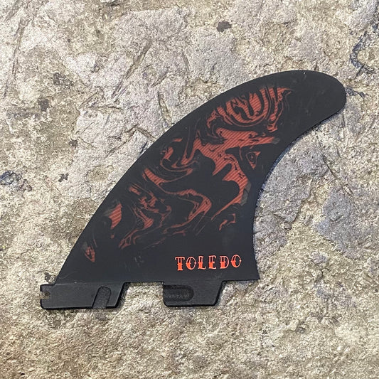 view of a single FCS II Filipe Toledo set in red and black laid on a concrete floor