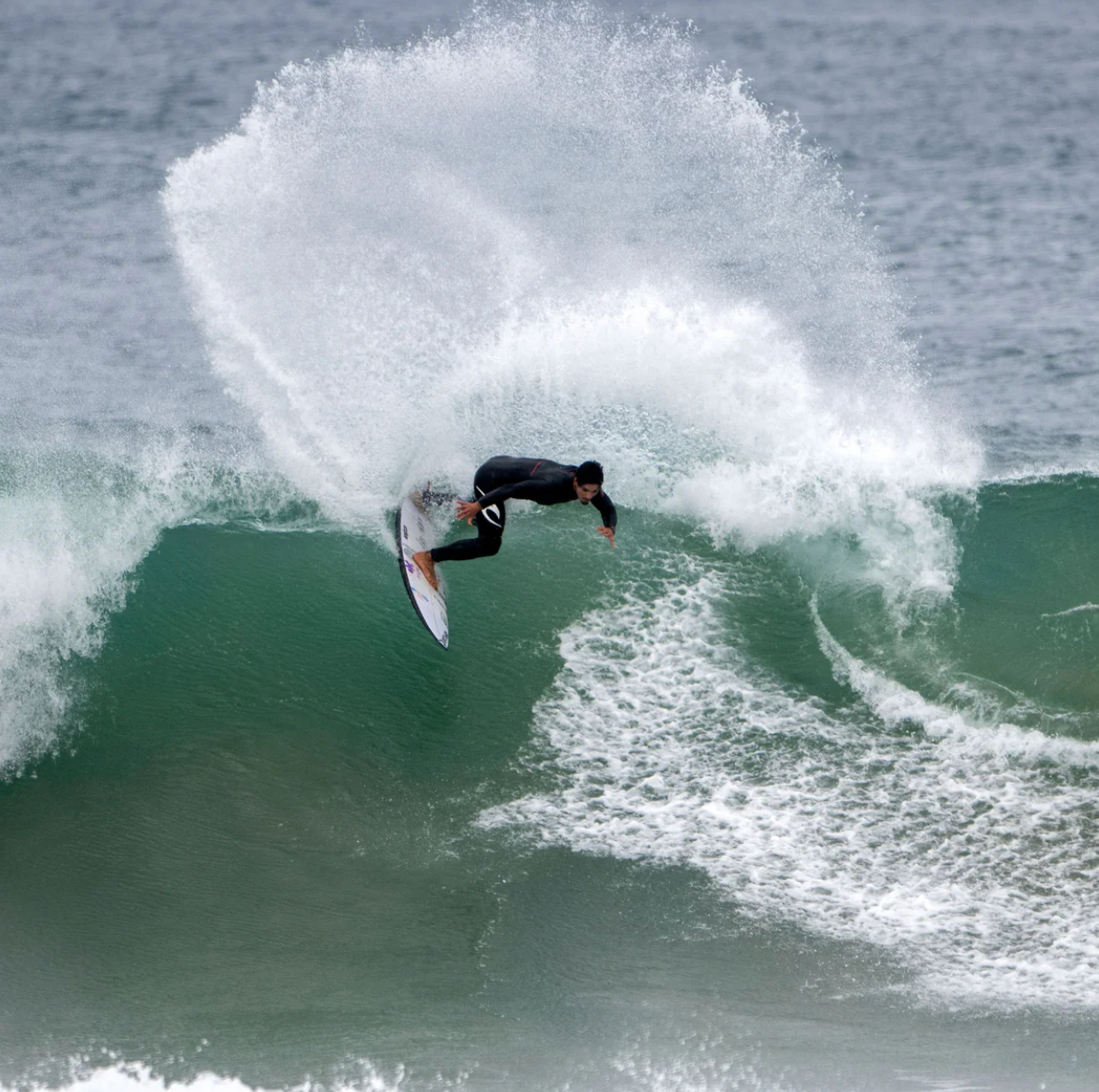 Gabriel Medina surfing with a set of FCS II Gabriel Medina Signature Tri Fins with red, black, and grey color scheme.