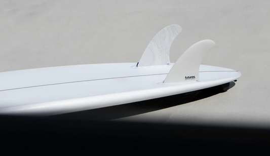 A set of white Futures Son Of Cobra Twin surfboard fins in a surfboard against a grey background