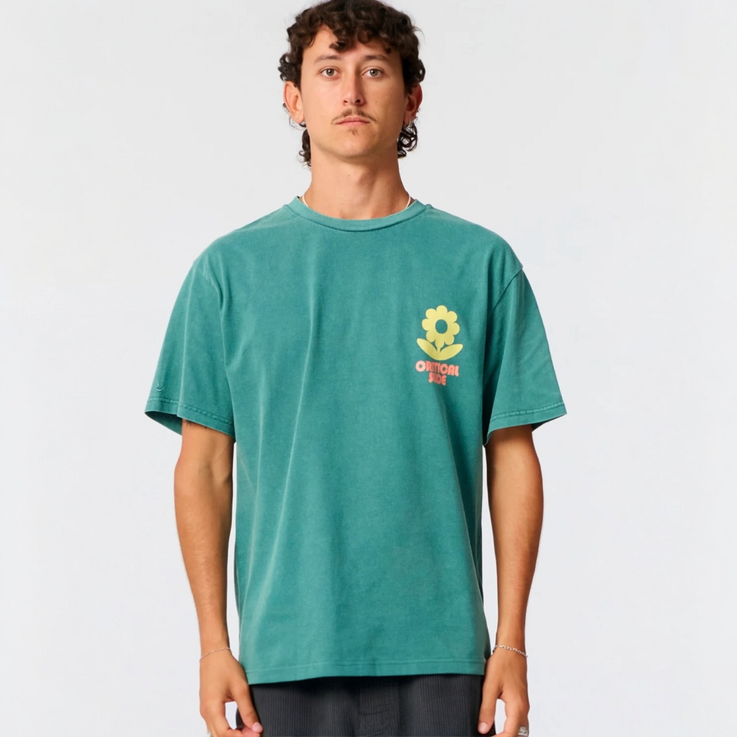 Person wearing a teal t-shirt with a logo on a plain background