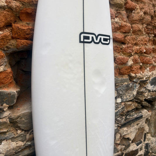 White surfboard with a black logo against a stone wall