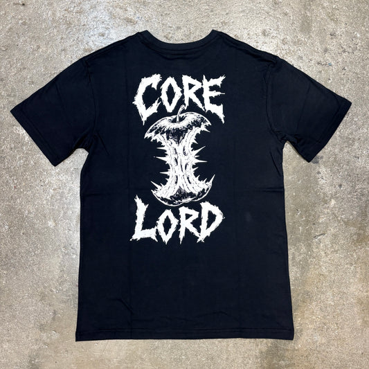 A black short-sleeve t-shirt laid flat on a textured concrete floor, featuring a large white graphic print on the back with the words 'CORE LORD' and a stylized thorn-like symbol.