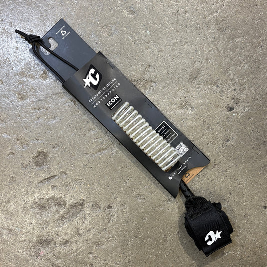 A white bodyboard leash with a white coiled leash line and a black wrist strap, shown attached to its black retail packaging card on a gray concrete floor. The packaging features the XC Surf brand logo and the model name ICON.