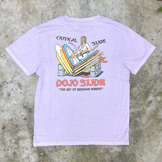 A light lavender heather t-shirt featuring a retro graphic of a surfer riding a slide with the text 'CRITICAL SLIDE' and 'DOJO SLIDE' on a concrete background.