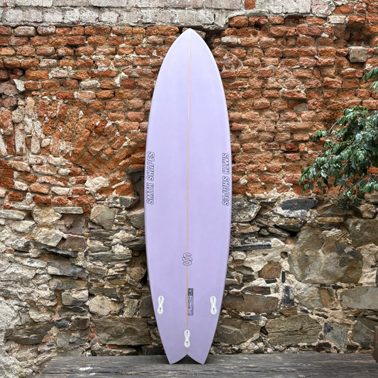 Purple SMTH surfboard leaning against a rustic stone wall.