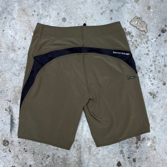 Brown shorts with black waistband on a textured gray surface