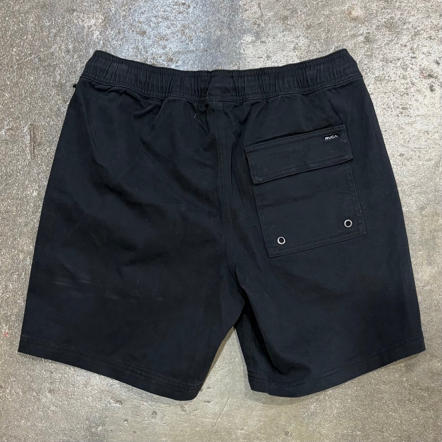 Black shorts with a pocket on a concrete surface