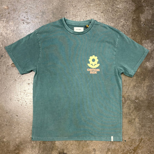 Green t-shirt with a yellow flower logo on a textured surface