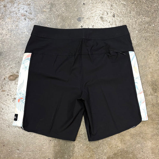 Black shorts with colorful side panels on a concrete surface
