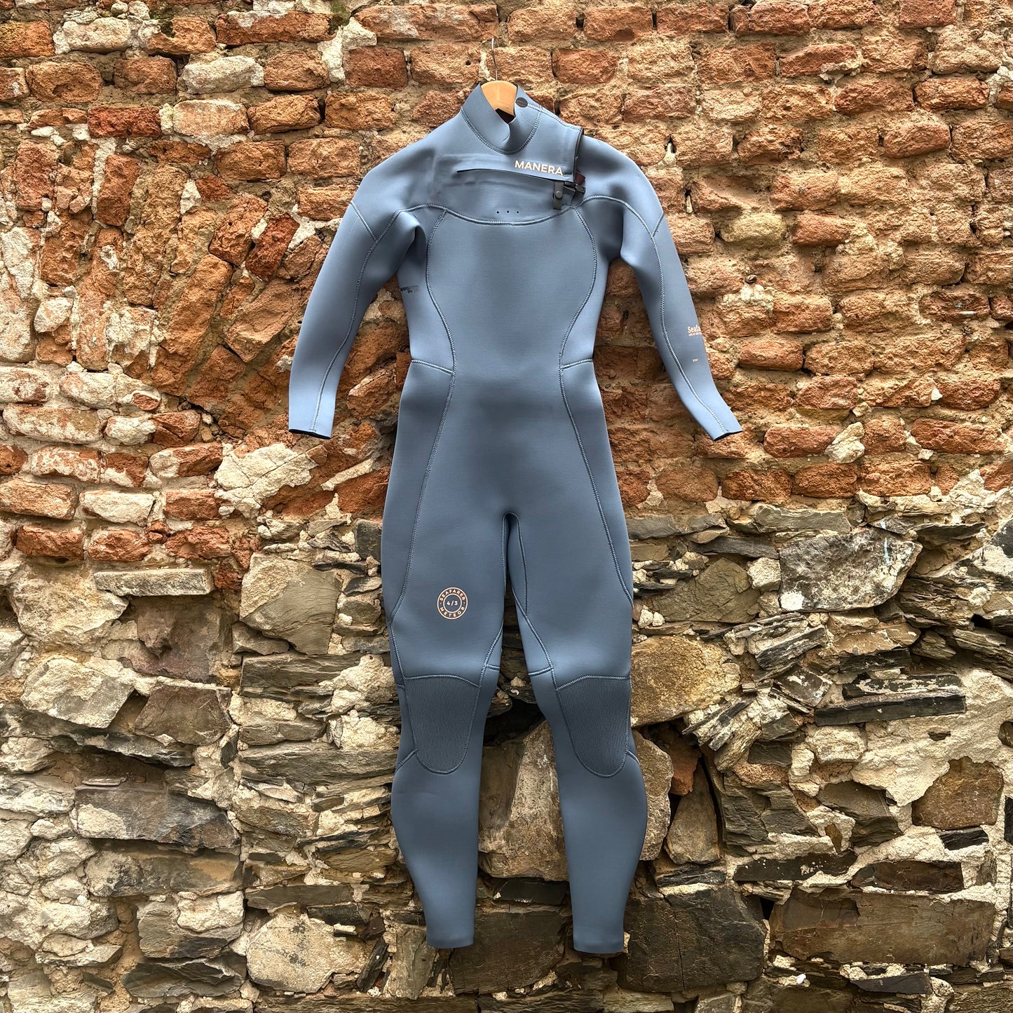 Blue wetsuit hanging on a brick wall