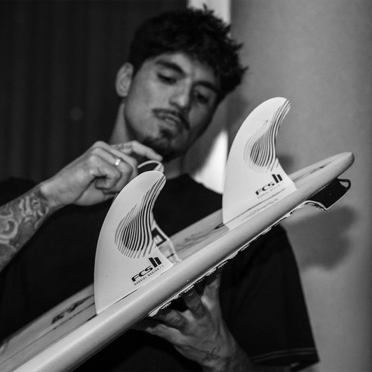 Gabriel Medina holding a surfboard with fins, black and white photo