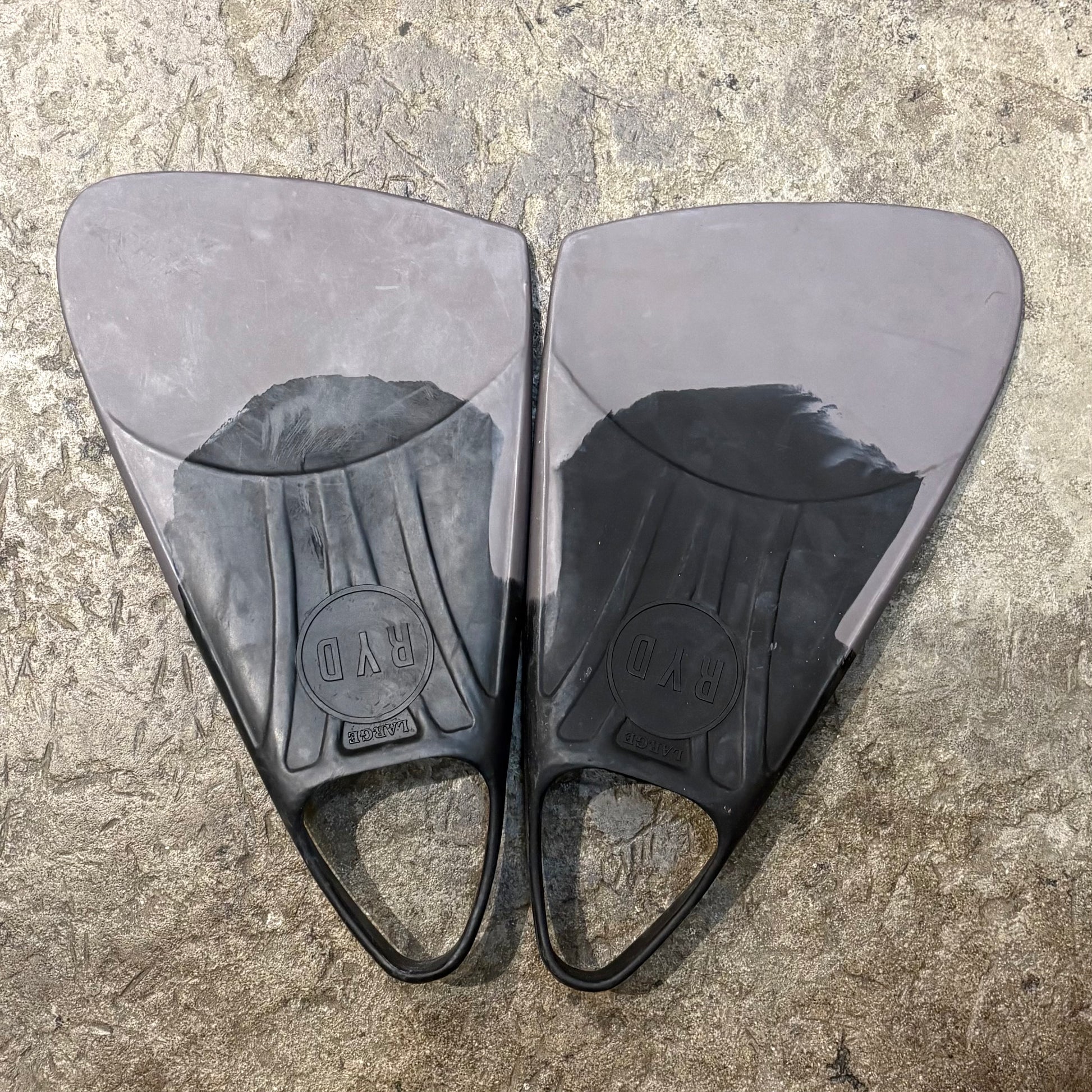 Pair of black swim fins on a textured surface