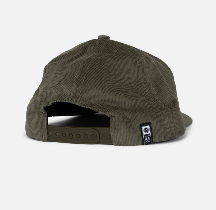 An olive green corduroy snapback cap shown from the back, featuring a small black and white brand patch on the side and a dark adjustable strap.