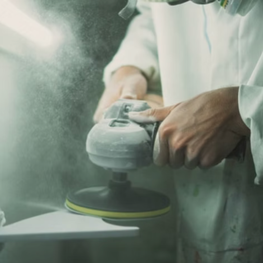 Person using a sanding machine with dust in a workshop setting
