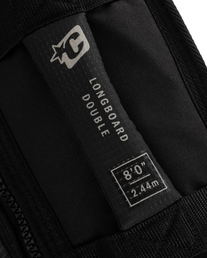 Close-up of a label on a black longboard deck with branding and dimensions.