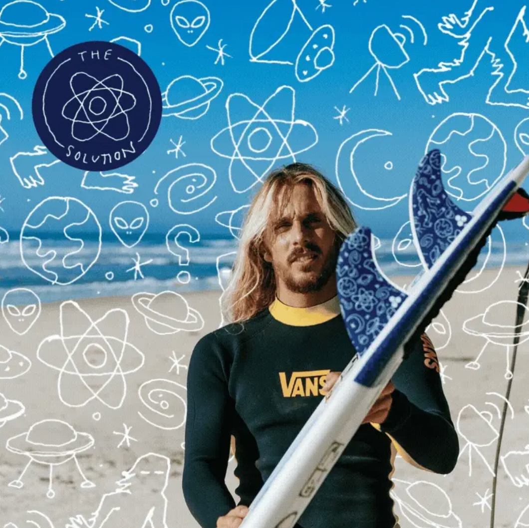 Man holding a Channel Islands surfboard with a blue and white pattern against a beach background with abstract designs.