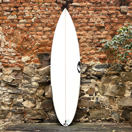 White SharpEye Synergy ( Jack Robinson Model ) 6'4"   20   2.68  35.4L surfboard leaning against a rustic stone wall.