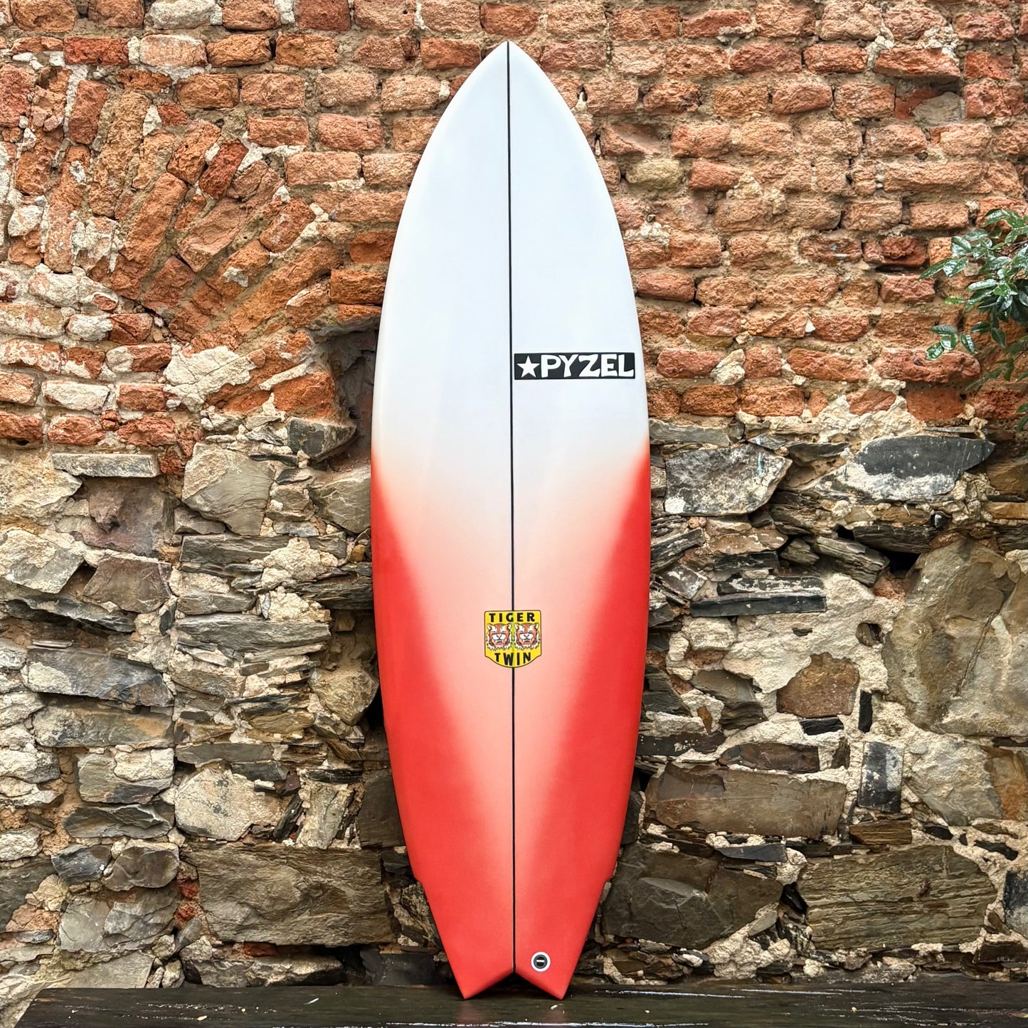TIGER TWIN 5'6" 20" 2.56" 31L Surfboard with a gradient design against a stone wall.