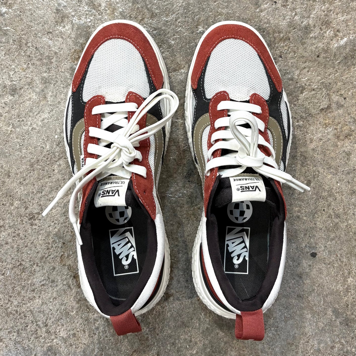 Pair of Vans sneakers with red, white, and black design on a concrete surface