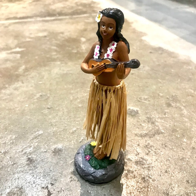 Dashboard Hula Doll playing guitar on a concrete surface