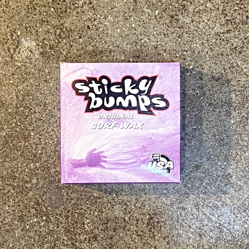 A box of Sticky Bumps Original Surf Wax with a pink and purple design, indicating cold water temperature suitability and the brand's logo.