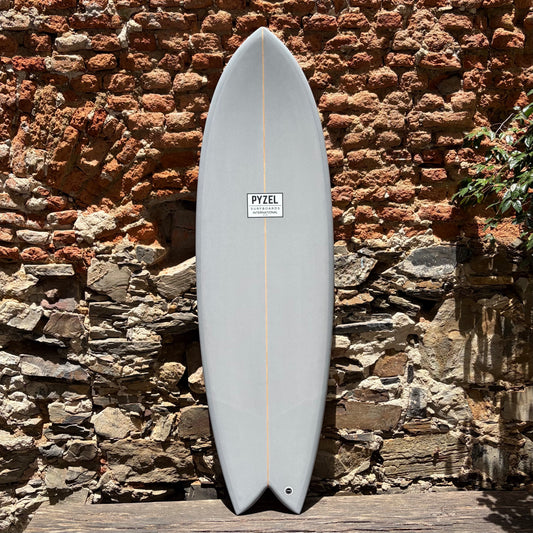 Surfboard with a visible Pyzel brand logo against a stone wall.