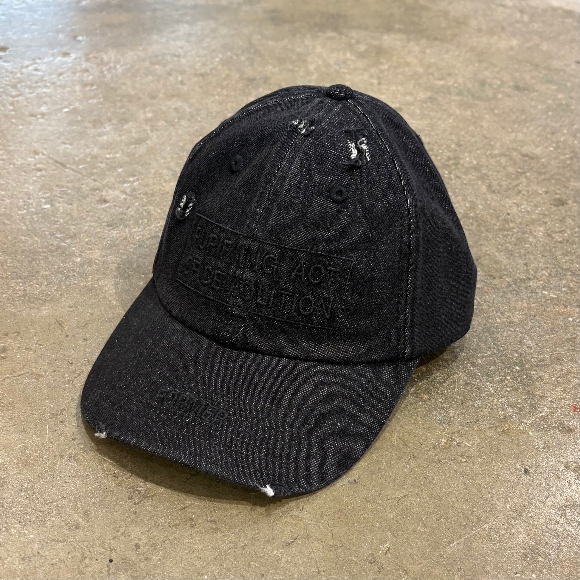 Black distressed baseball cap with text on a concrete surface