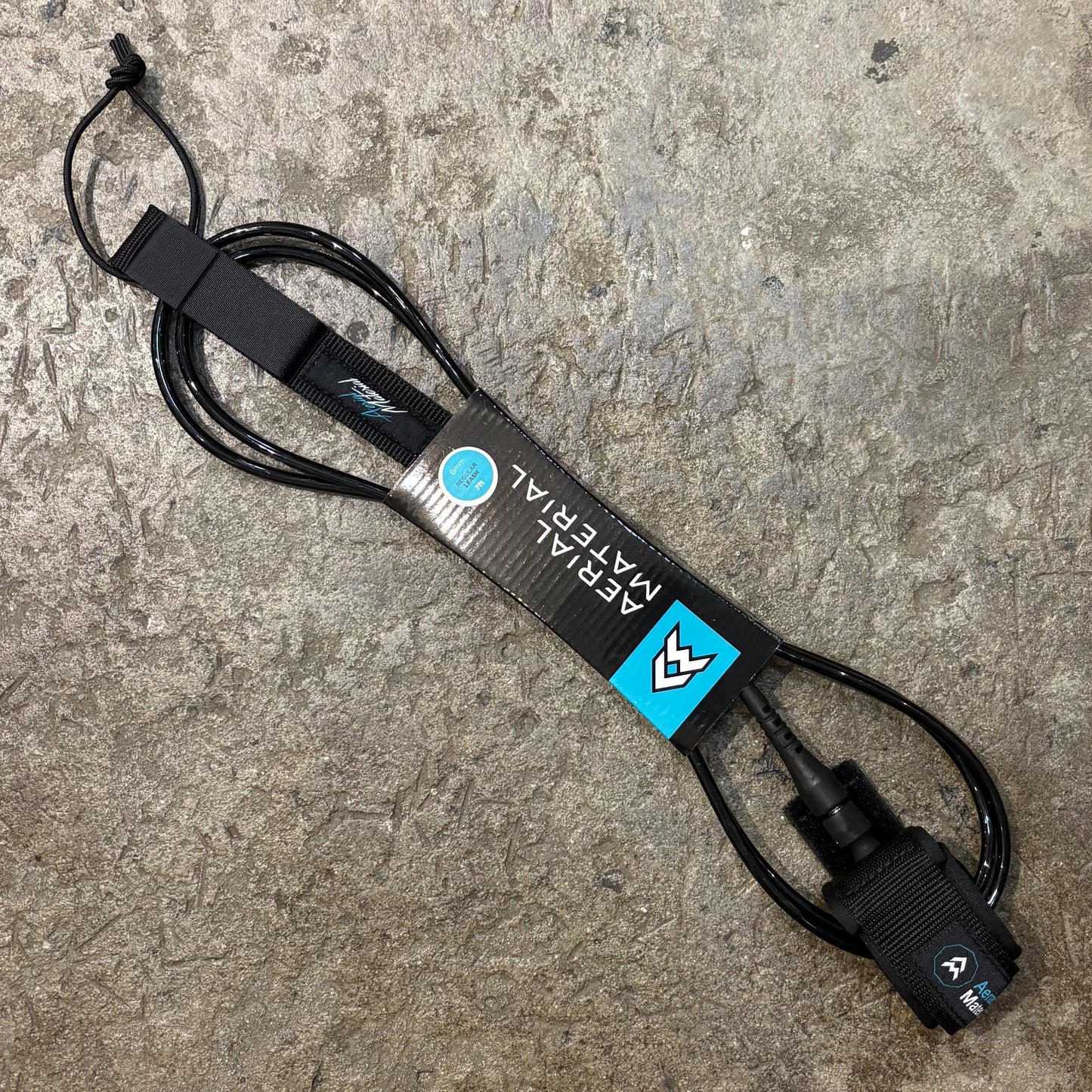 Surfboard leash with brand logo on a concrete surface