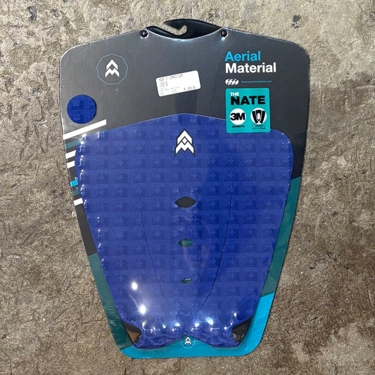 Blue and black surfboard tail pad with branding on a textured surface
