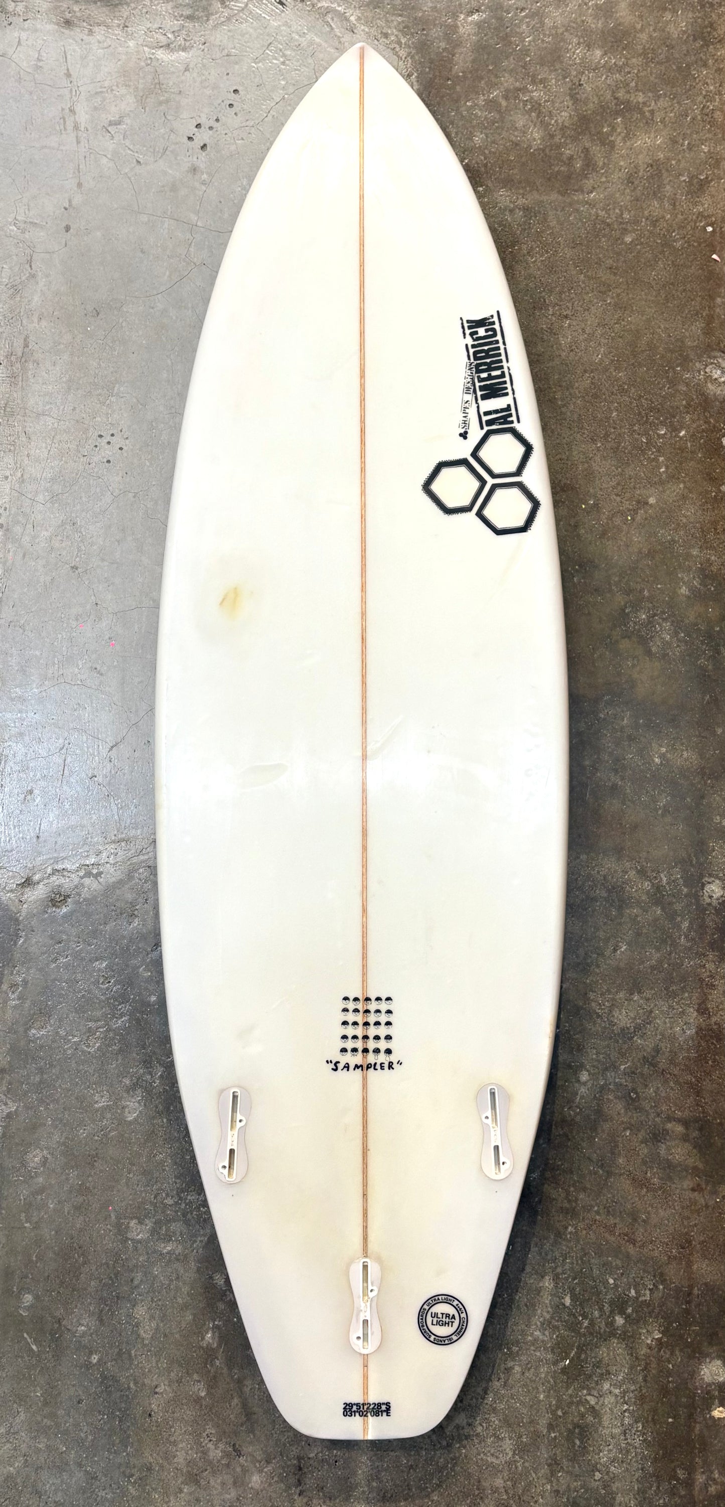 White surfboard with branding on a textured gray surface