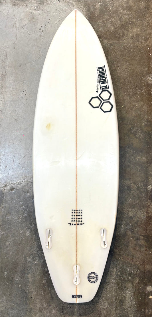 White surfboard with branding on a textured gray surface