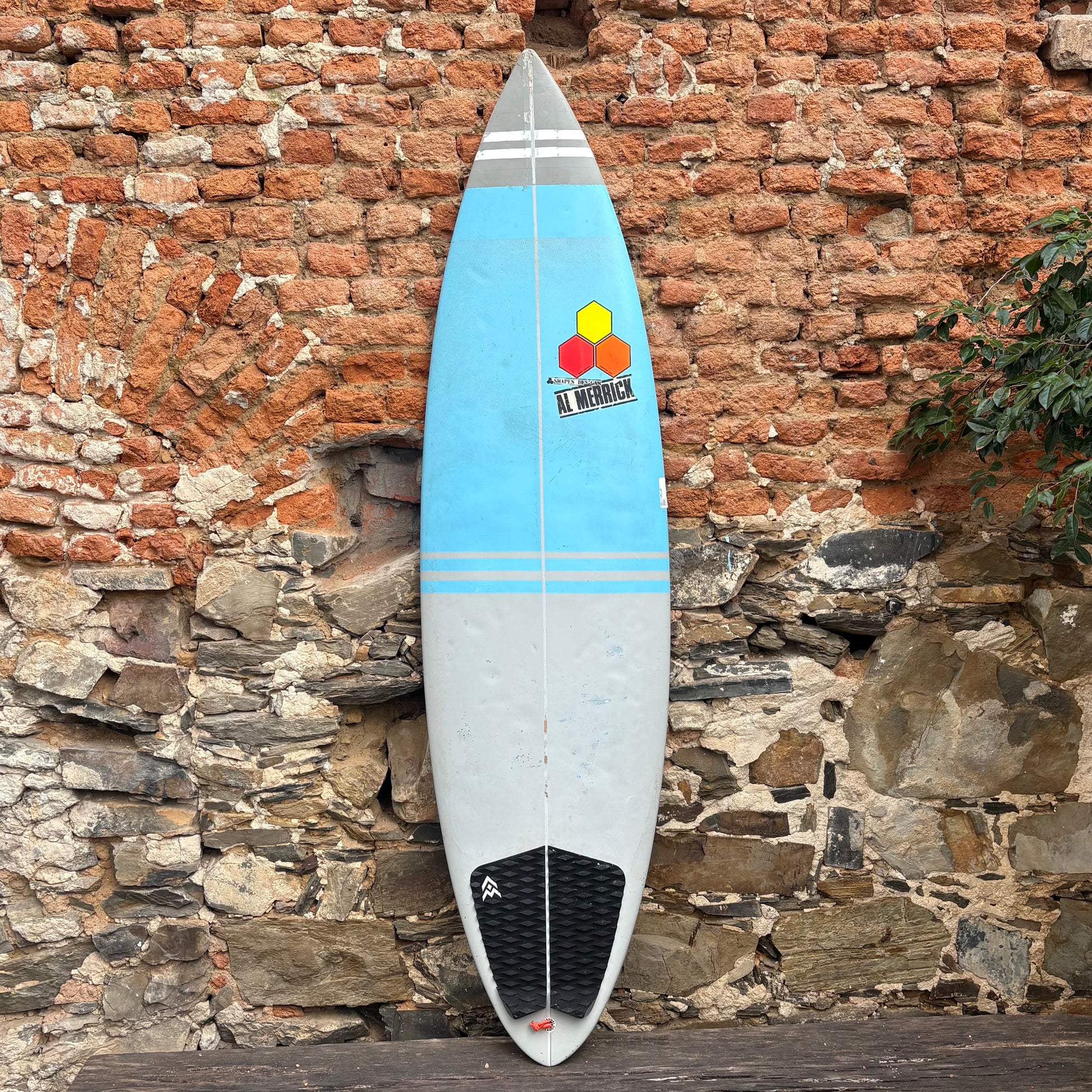 Channel Islands Taco Grinder Surfboard with a colorful design leaning against a stone wall.