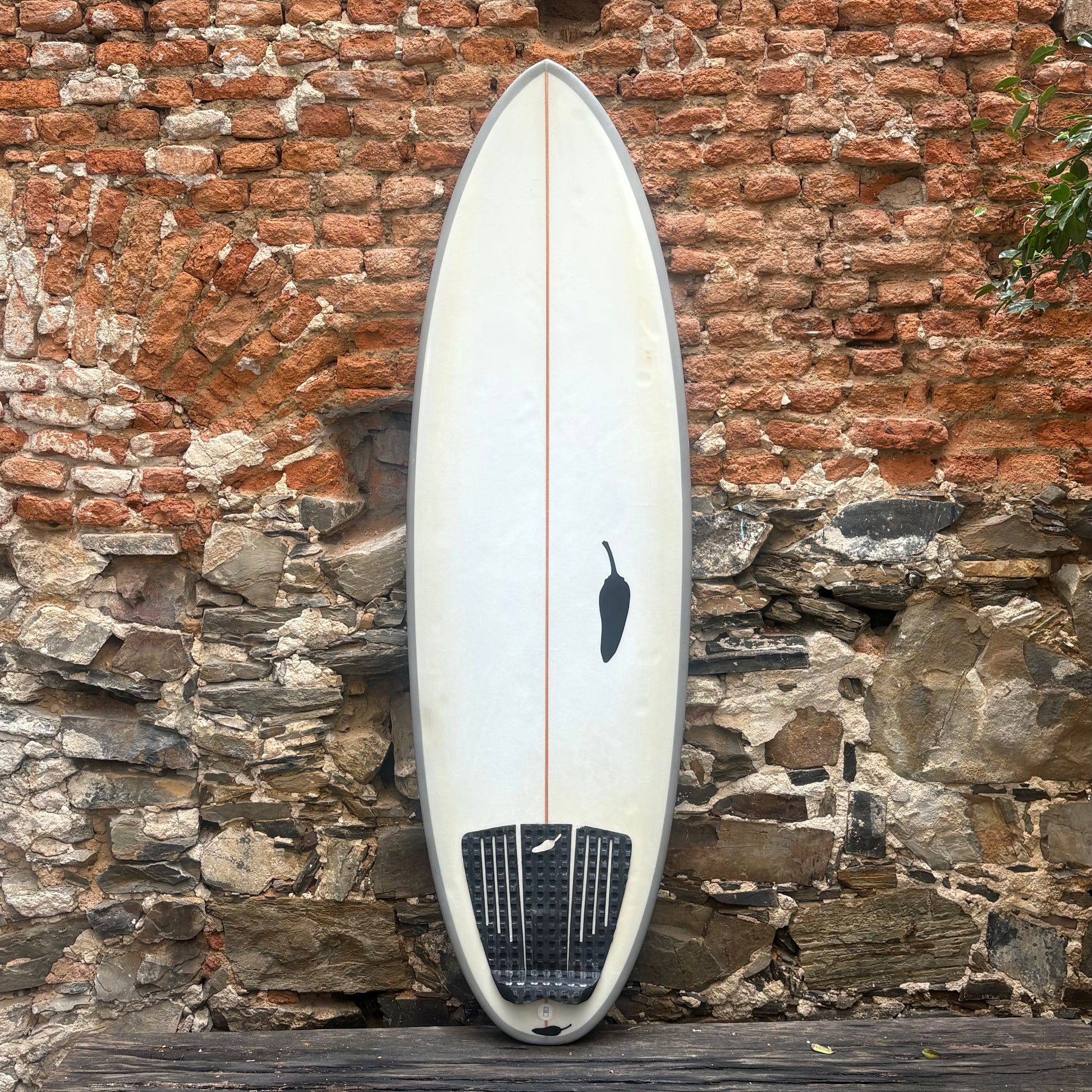 Surfboard leaning against a rustic stone wall