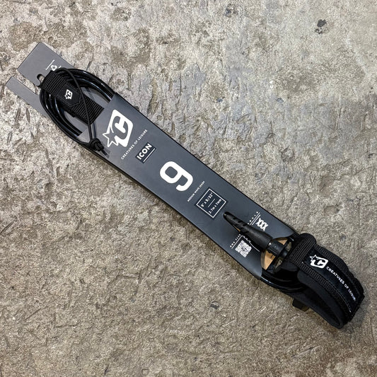 A blue and black ICON 9 surf leash with a swivel bearing and a label detailing the product specifications placed on a textured ground.