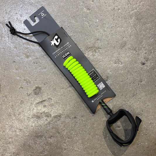 A lime colored  coiled leash with a bright neon green handle, packaged on a black branded card and placed on a textured gray concrete surface.