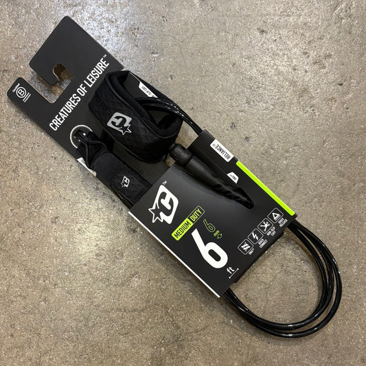 Black leash with packaging on a concrete surface