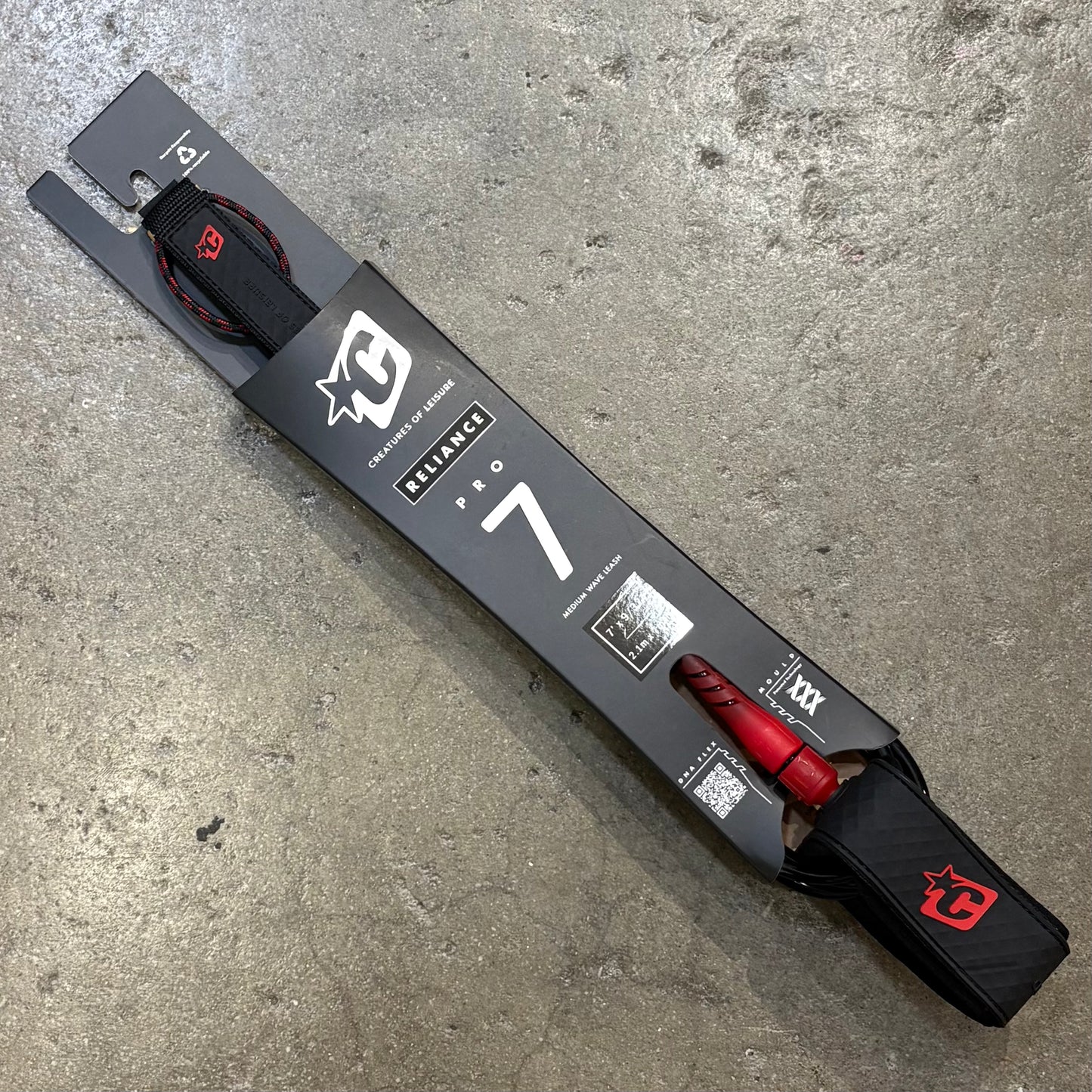 Black and red ski with packaging on a concrete surface