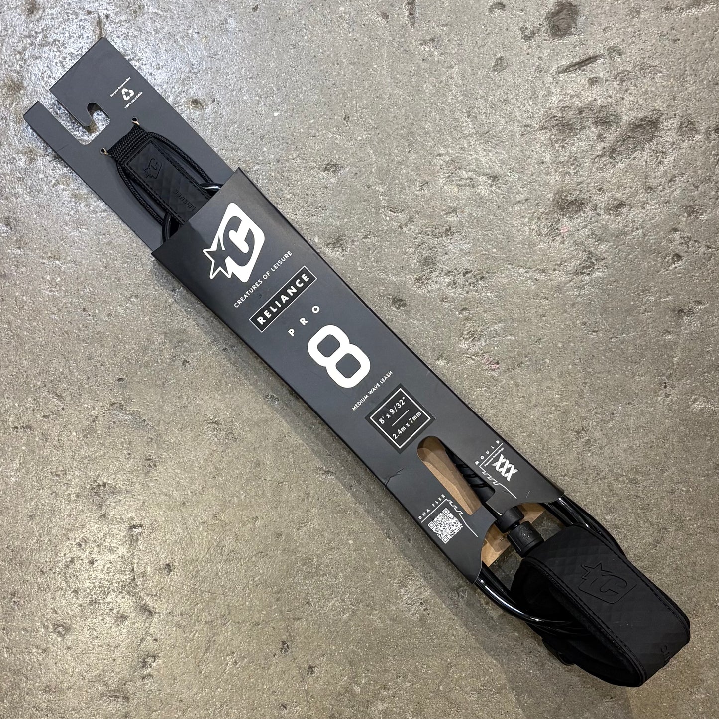 Black ski binding on a concrete surface with visible branding.