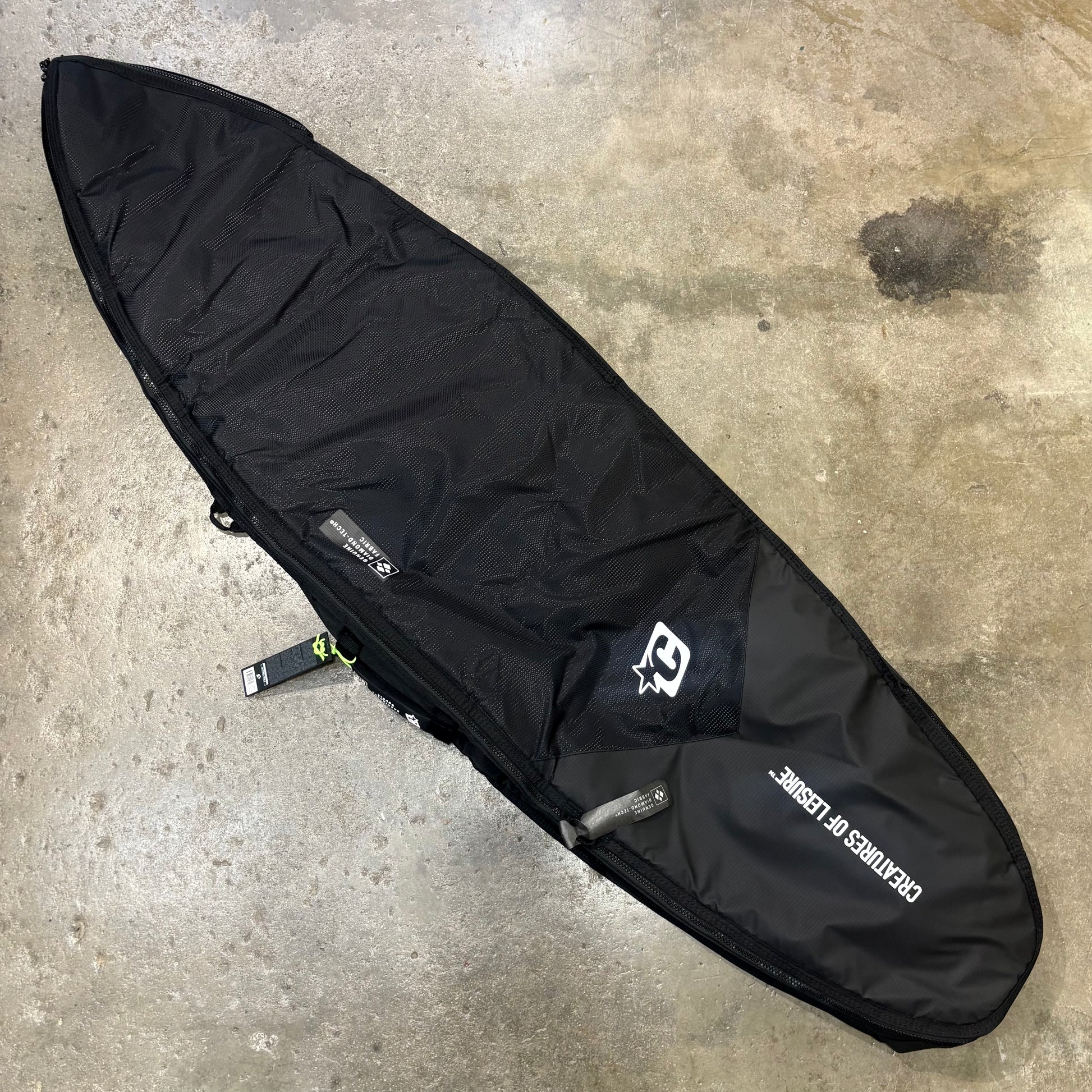 Black surfboard bag with a brand logo on a concrete surface