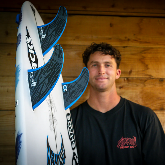 Man holding a surfboard with a wooden wall background