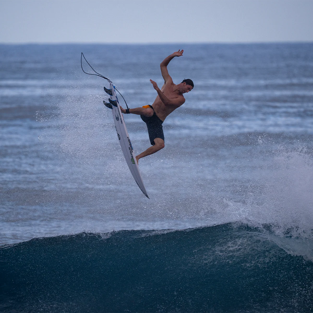 Surfer performing a trick on a wave with a clear sky background