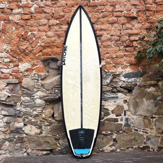 Dutchie Surfboard leaning against a stone wall with a brick background