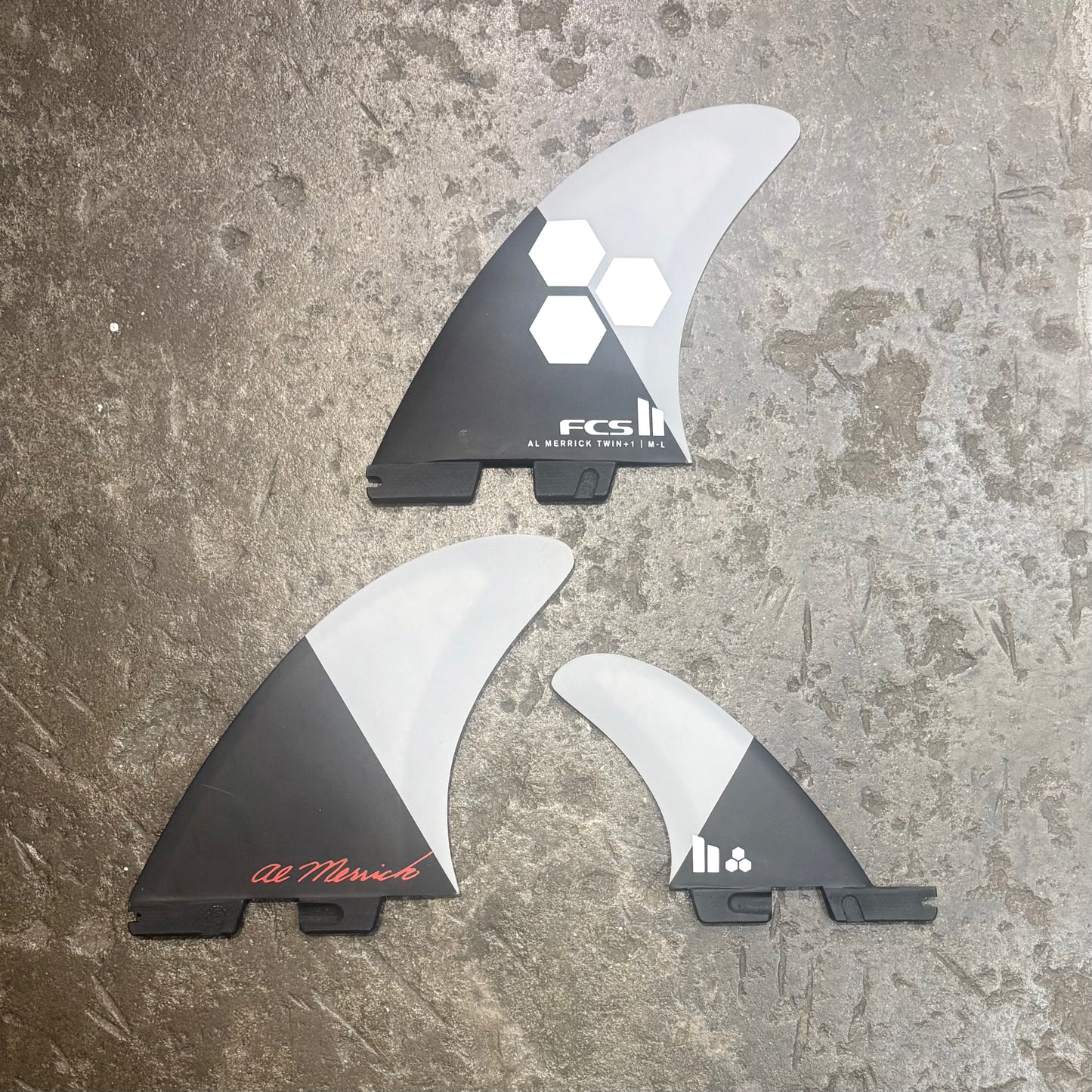 Three surfboard fins with FCS branding on a textured surface