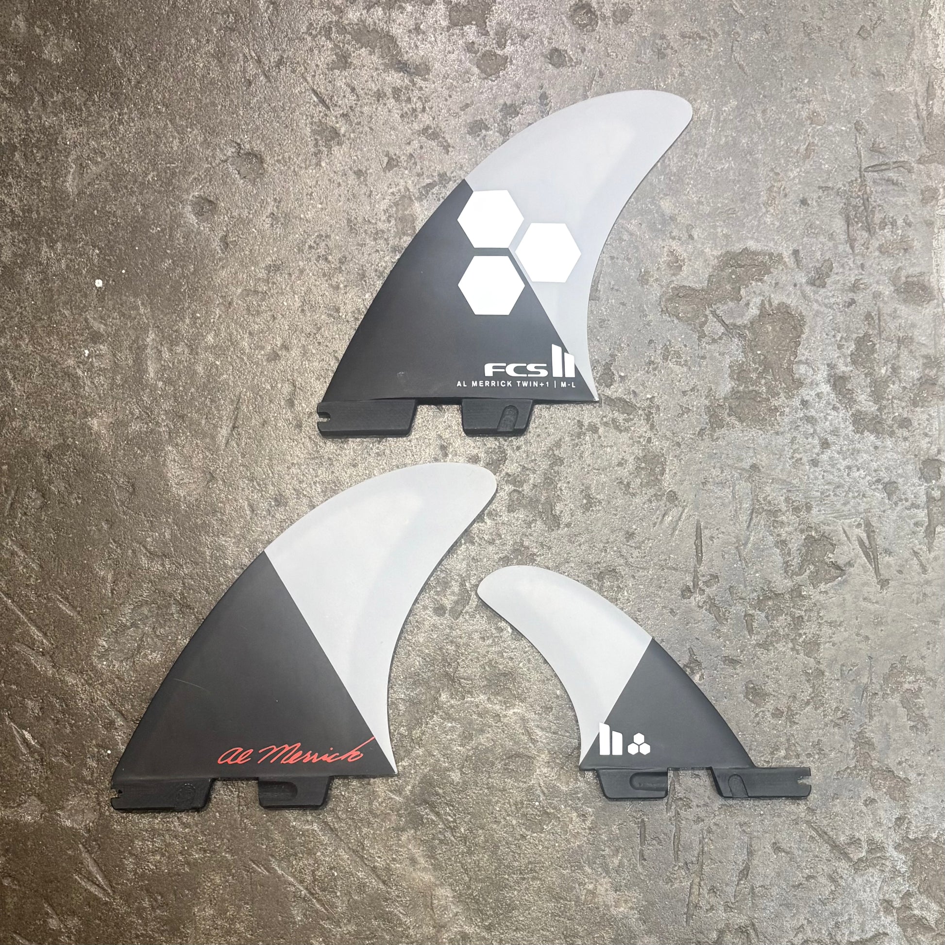 Three surfboard fins with FCS branding on a textured surface