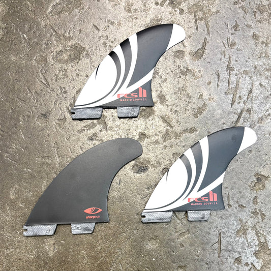 Three surfboard fins with FCS logo on a textured surface