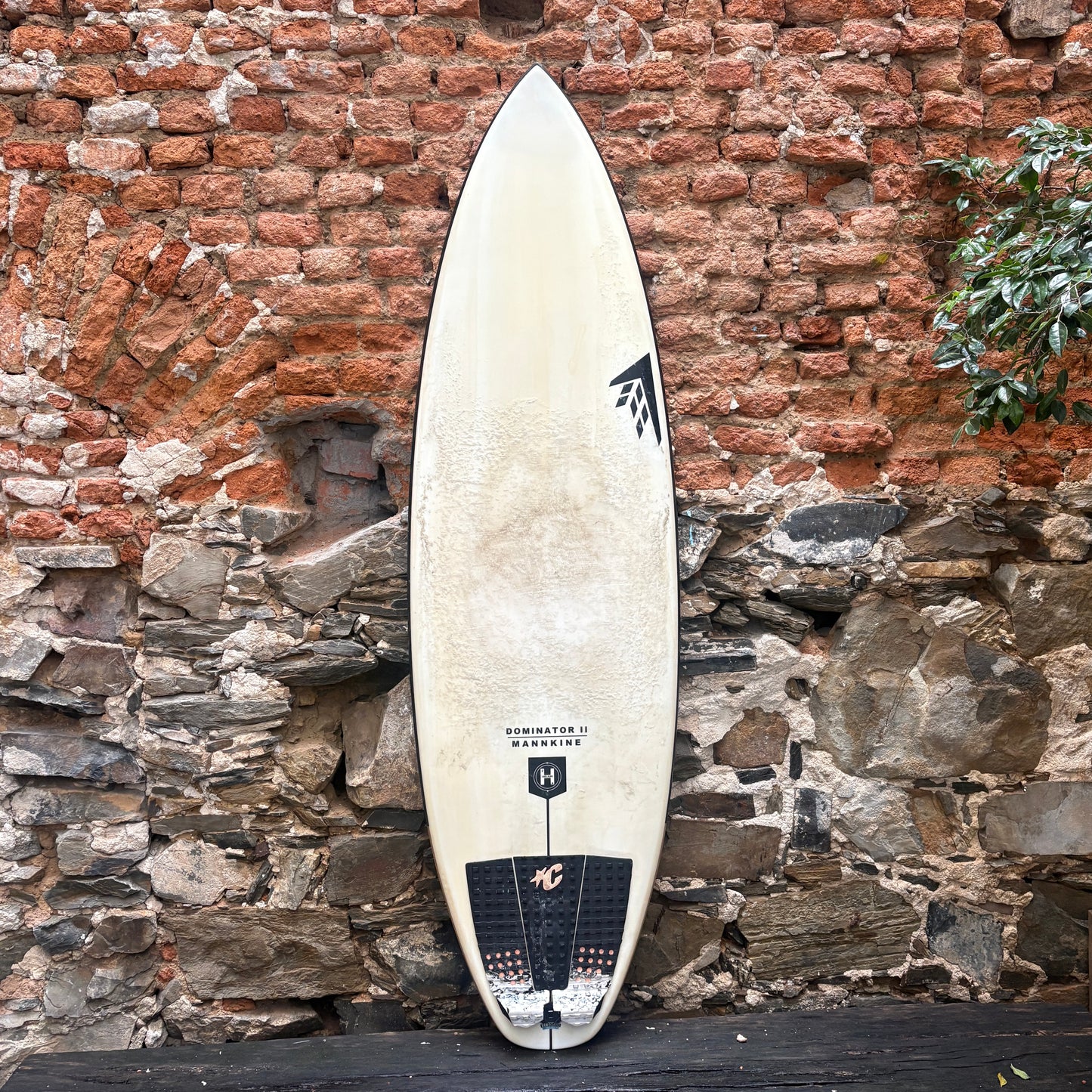 Surfboard leaning against a brick wall with stone accents