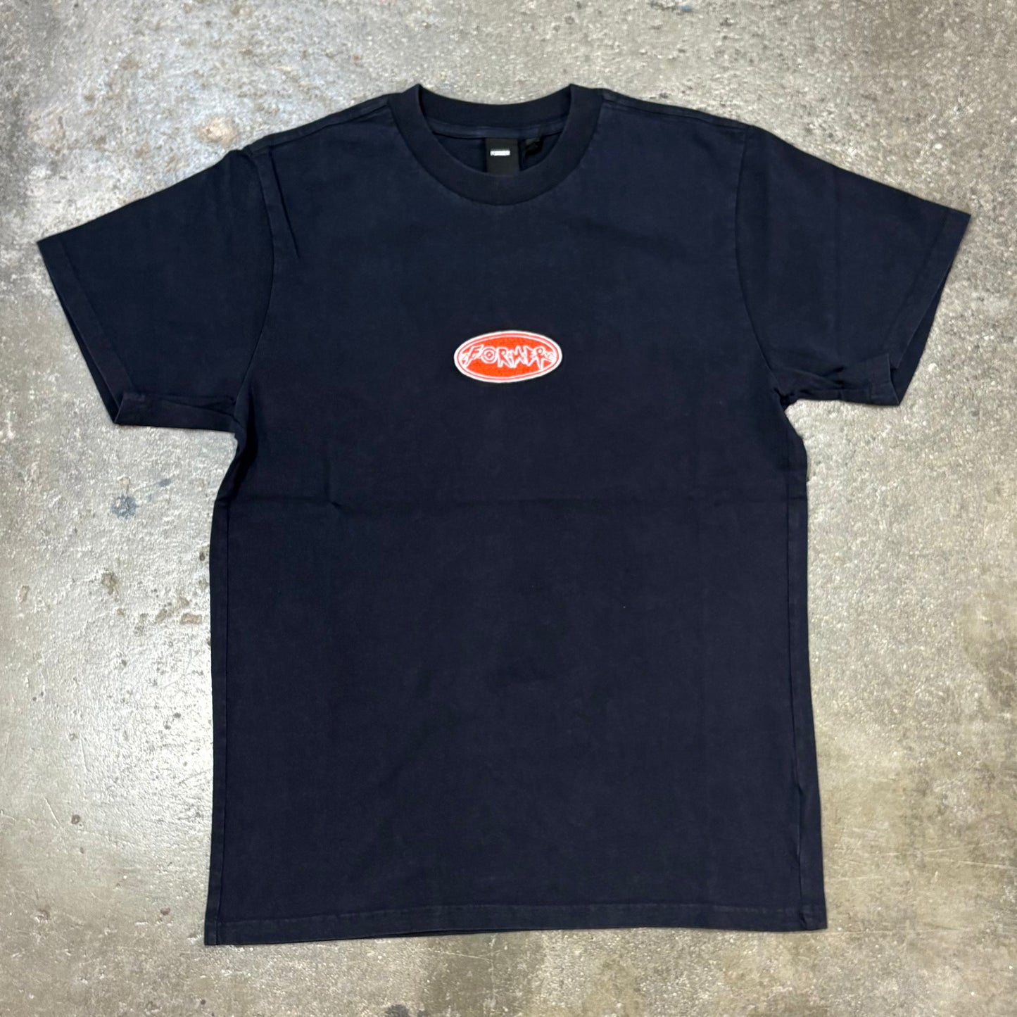 Black t-shirt with a logo on a concrete surface