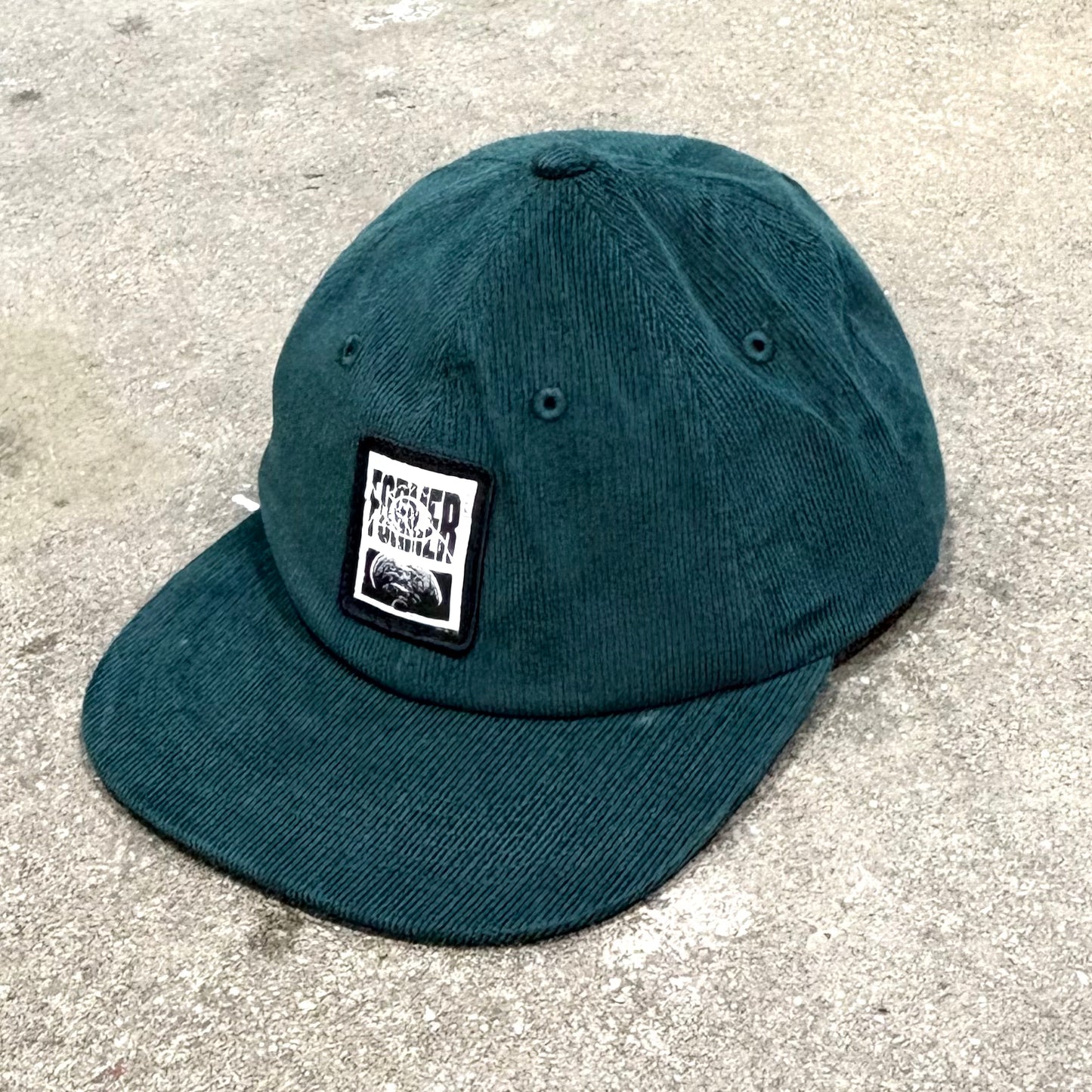 Teal cap with a logo on a concrete surface